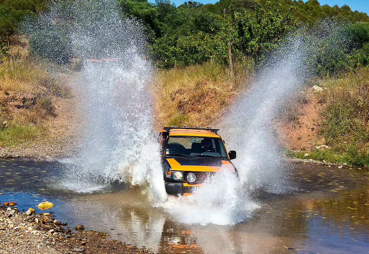 Orange jeep splashing through an Algarve river crossing